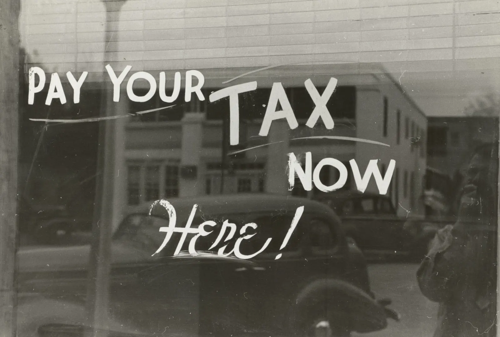 sign on window saying pay your tax now